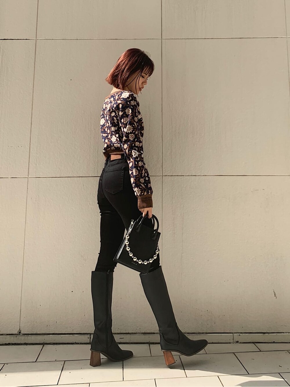 ブラック系のデニムパンツ、ブラック系のショルダーバッグ、ブラック系のブーツを着用したレディースの秋コーディネートの2枚目の写真