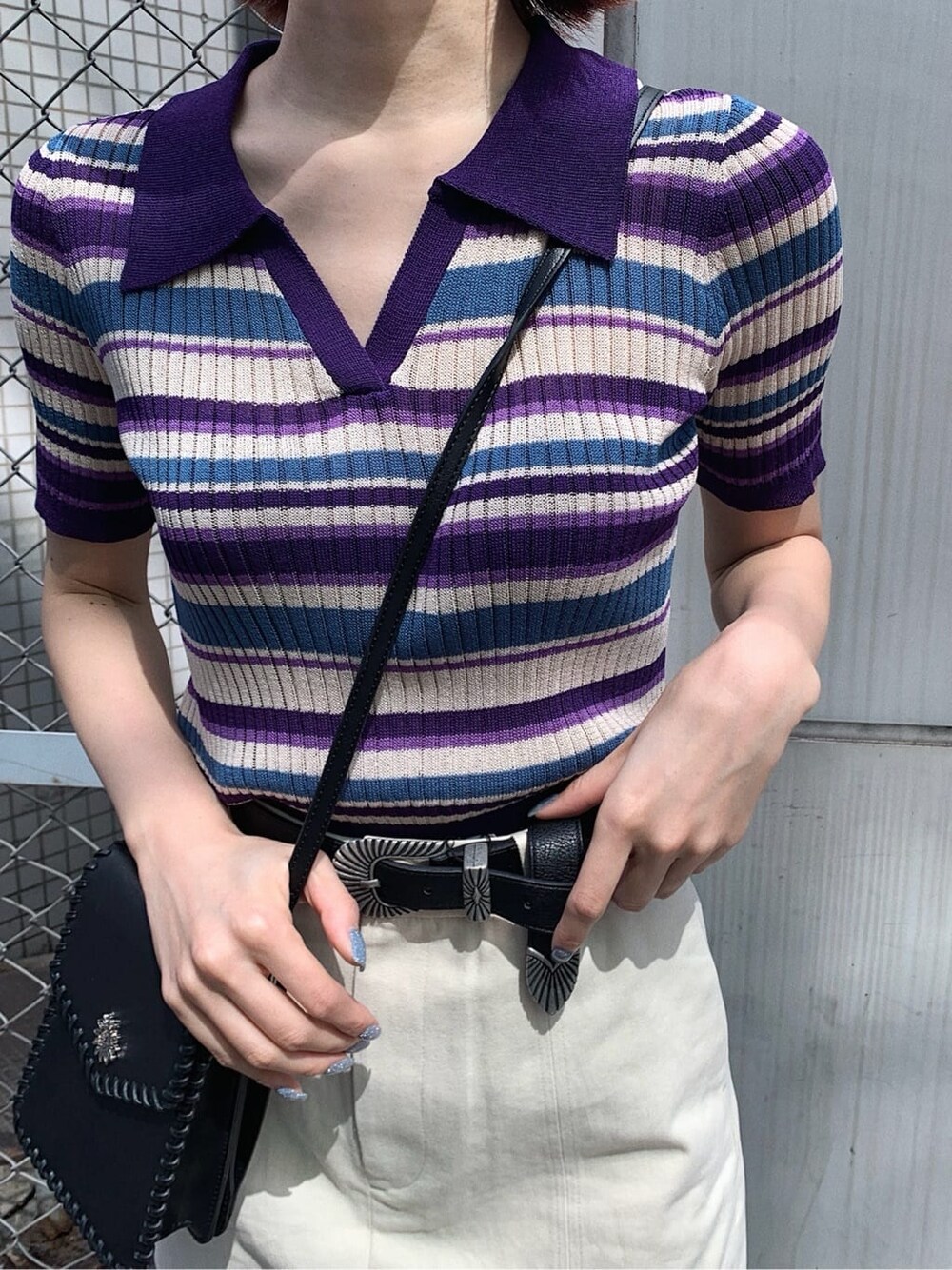 ブラック系のショルダーバッグ、ホワイト系のスカート、パープル系のニット/セーターを着用したレディースの春コーディネートの5枚目の写真