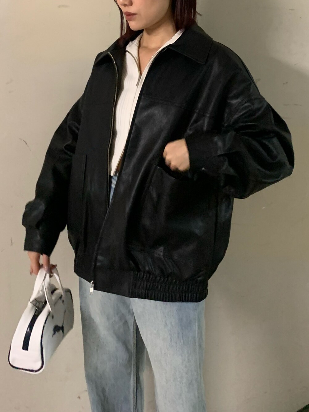 ホワイト系のニット/セーター、ブラック系のブルゾン、ブルー系のデニムパンツを着用したレディースの秋コーディネートの4枚目の写真