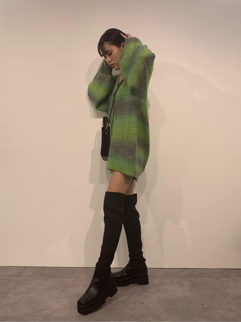 グリーン系のカーディガン/ボレロ、ブラック系のブーツ、ブラック系のショルダーバッグを着用したレディースの秋コーディネートの2枚目の写真