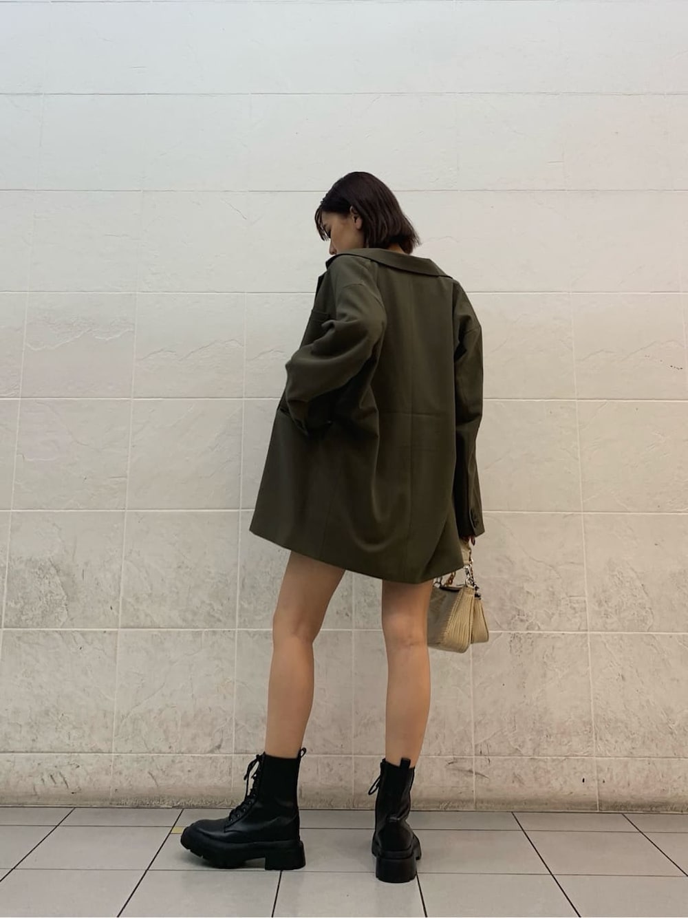 ホワイト系のキャミソール、ベージュ系のテーラードジャケット、ブラック系のブーツを着用したレディースの秋コーディネートの2枚目の写真