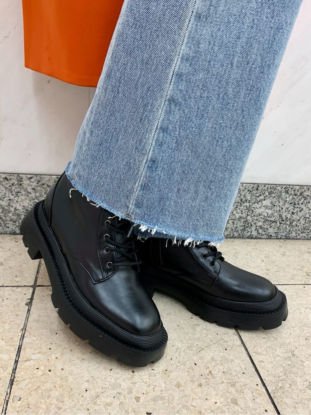 ブラック系のショルダーバッグ、オレンジ系のトレンチコート、ブルー系のデニムパンツを着用したレディースの冬コーディネートの10枚目の写真