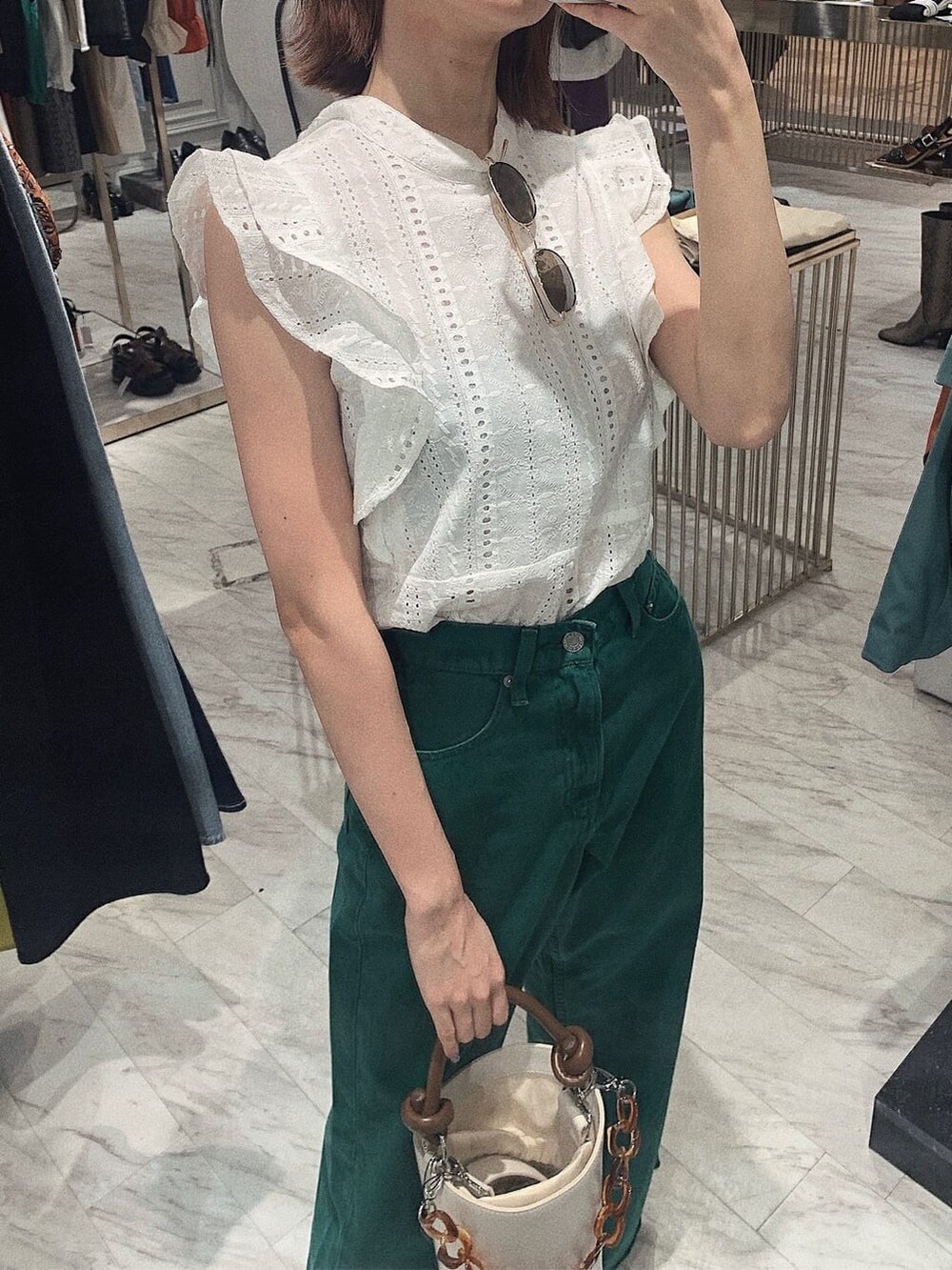 グリーン系のデニムパンツ、ホワイト系のタンクトップ、ホワイト系のサンダルを着用したレディースの春コーディネートの3枚目の写真