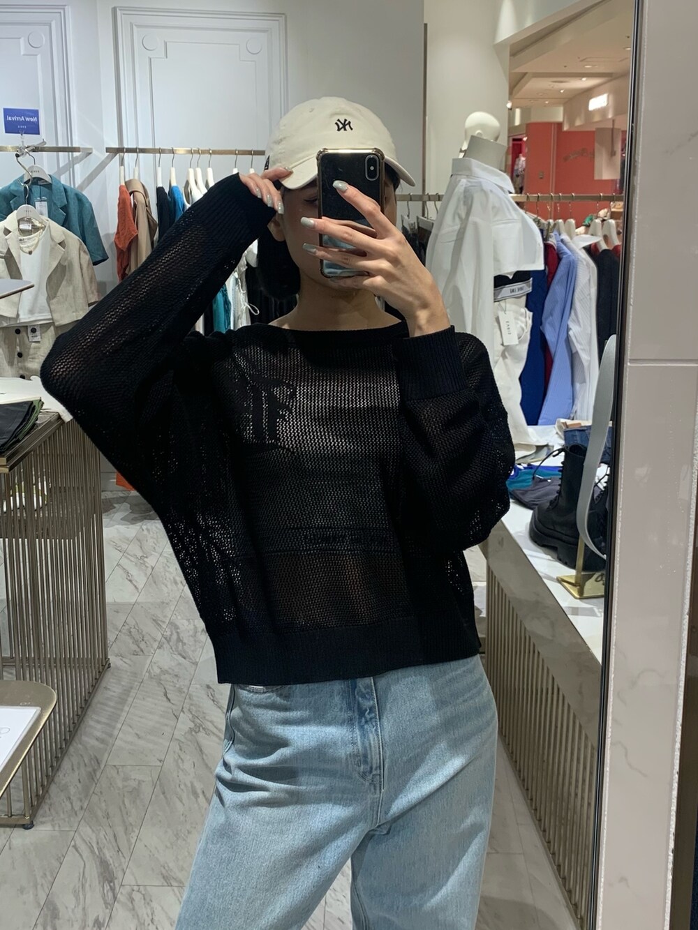 ブルー系のデニムパンツ、ブラック系のニット/セーター、ホワイト系のキャミソールを着用したレディースの春コーディネートの3枚目の写真