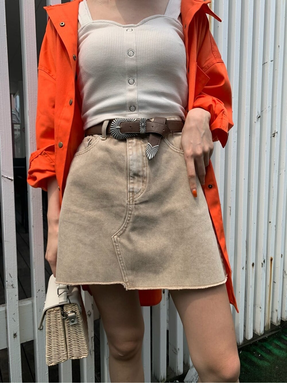 ブラック系のブーツ、ベージュ系のデニムスカート、オレンジ系のシャツ/ブラウスを着用したレディースの夏コーディネートの3枚目の写真