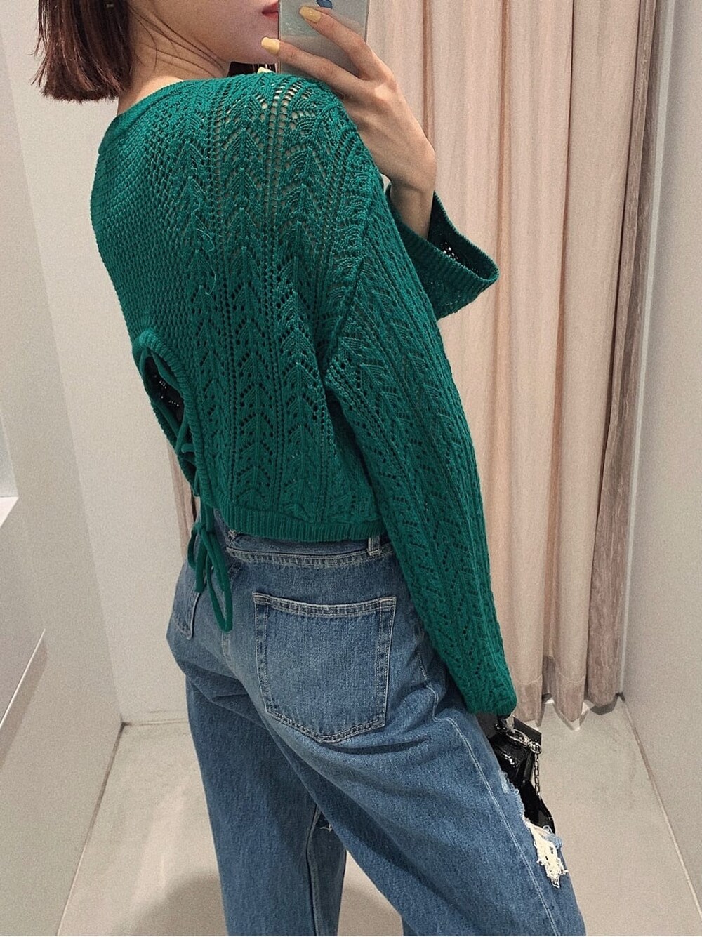 ブラック系のブーツ、ブルー系のデニムパンツ、グリーン系のニット/セーターを着用したレディースの春コーディネートの4枚目の写真