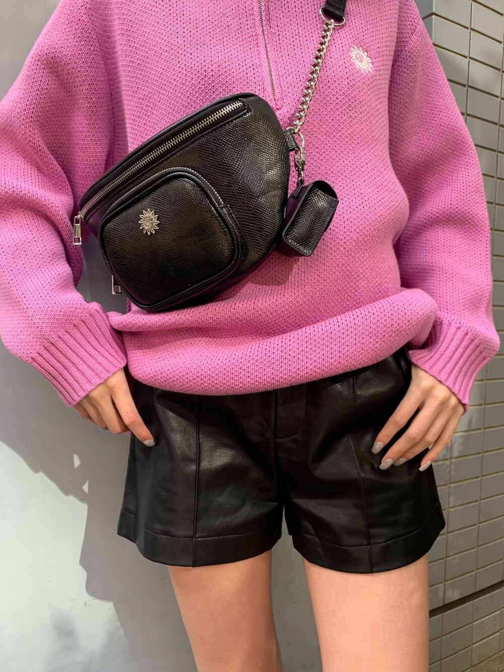 ピンク系のニット/セーター、ブラック系のブーツ、ブラック系のボディバッグ/ウエストポーチを着用したレディースの冬コーディネートの7枚目の写真