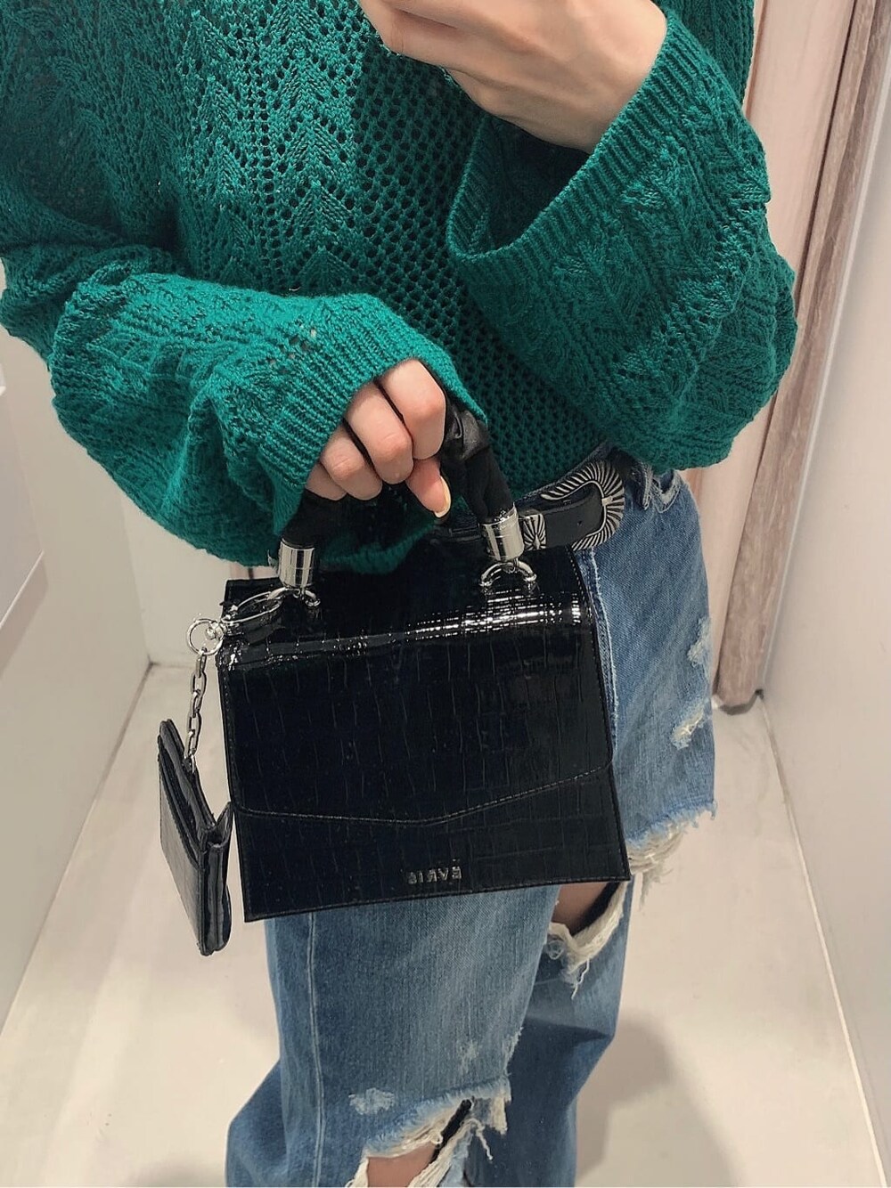 ブラック系のブーツ、ブルー系のデニムパンツ、グリーン系のニット/セーターを着用したレディースの春コーディネートの7枚目の写真