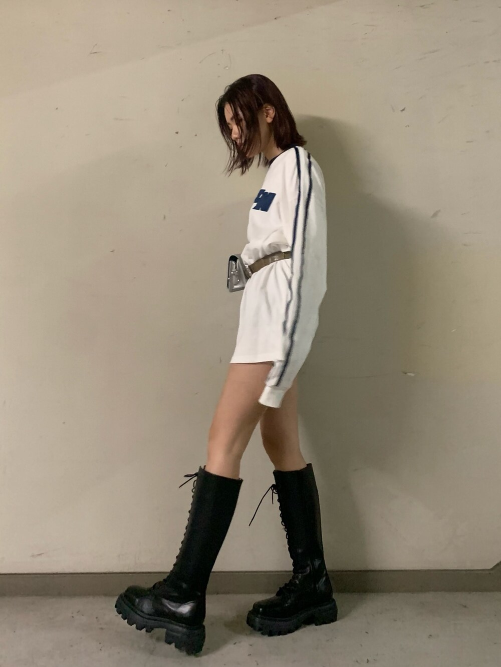 ホワイト系のワンピース、シルバー系のショルダーバッグ、ブラック系のブーツを着用したレディースの秋コーディネートの2枚目の写真