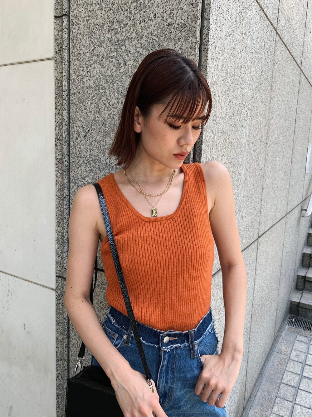 ブルー系のデニムパンツ、ブラック系のサンダル、オレンジ系のニット/セーターを着用したレディースの夏コーディネートの3枚目の写真