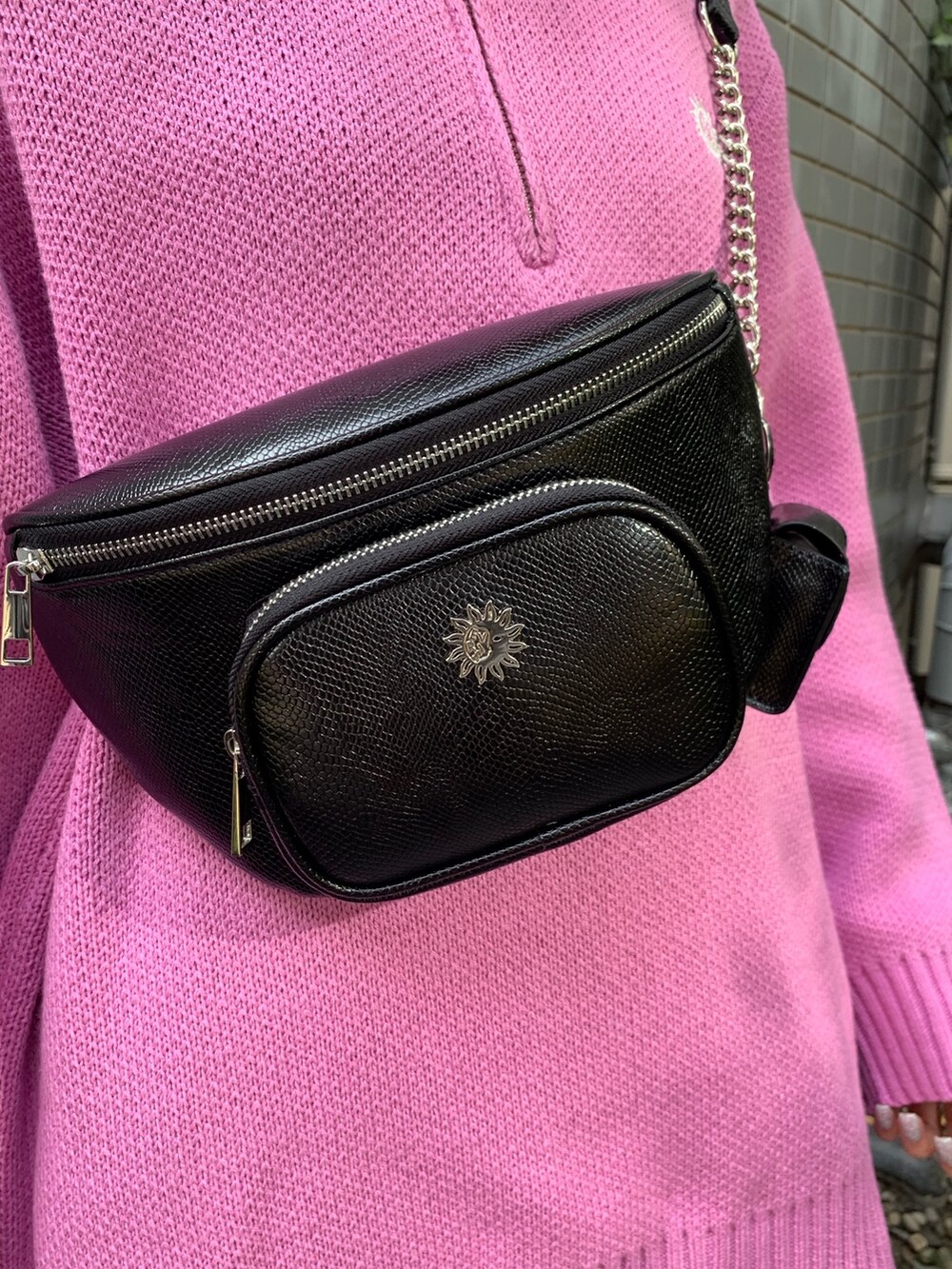 ピンク系のニット/セーター、ブラック系のブーツ、ブラック系のボディバッグ/ウエストポーチを着用したレディースの冬コーディネートの5枚目の写真