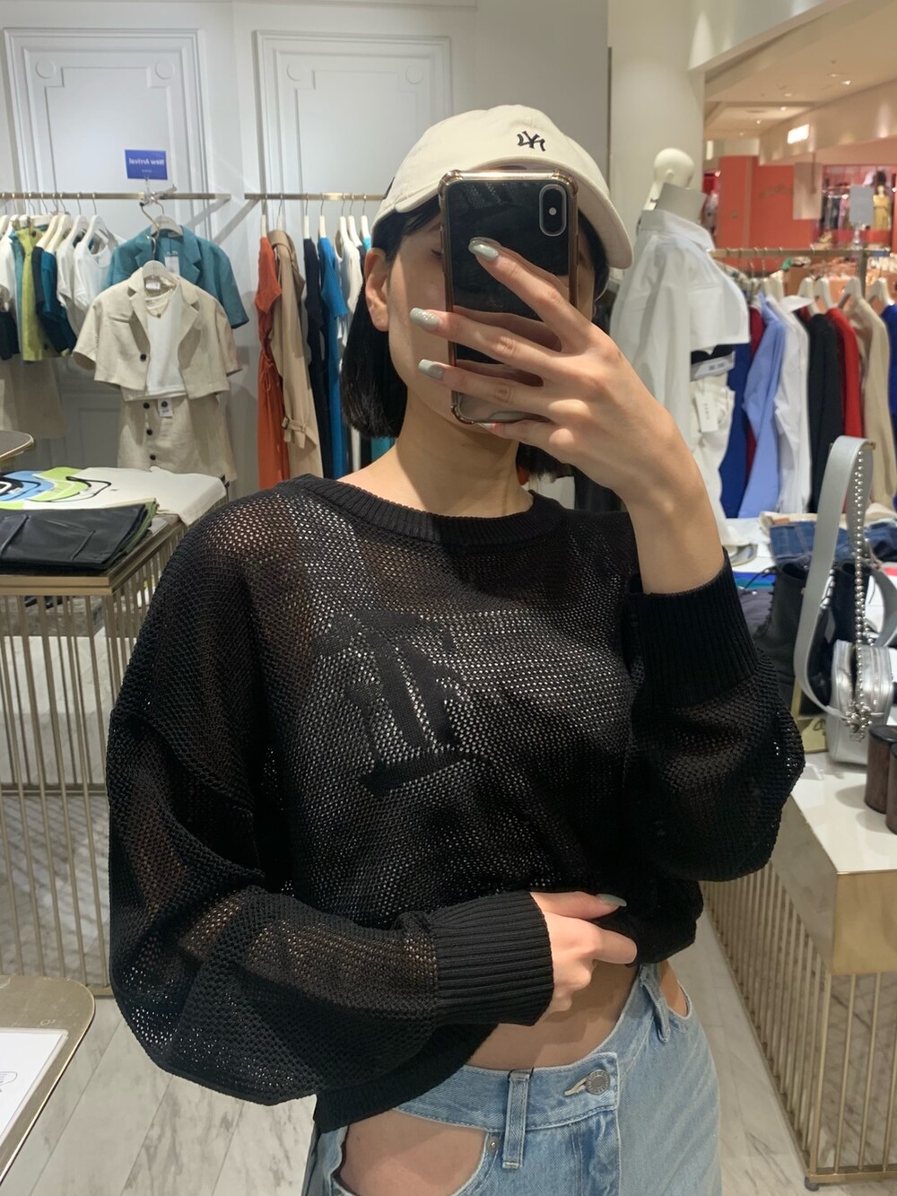 ブルー系のデニムパンツ、ブラック系のニット/セーター、ホワイト系のキャミソールを着用したレディースの春コーディネートの4枚目の写真