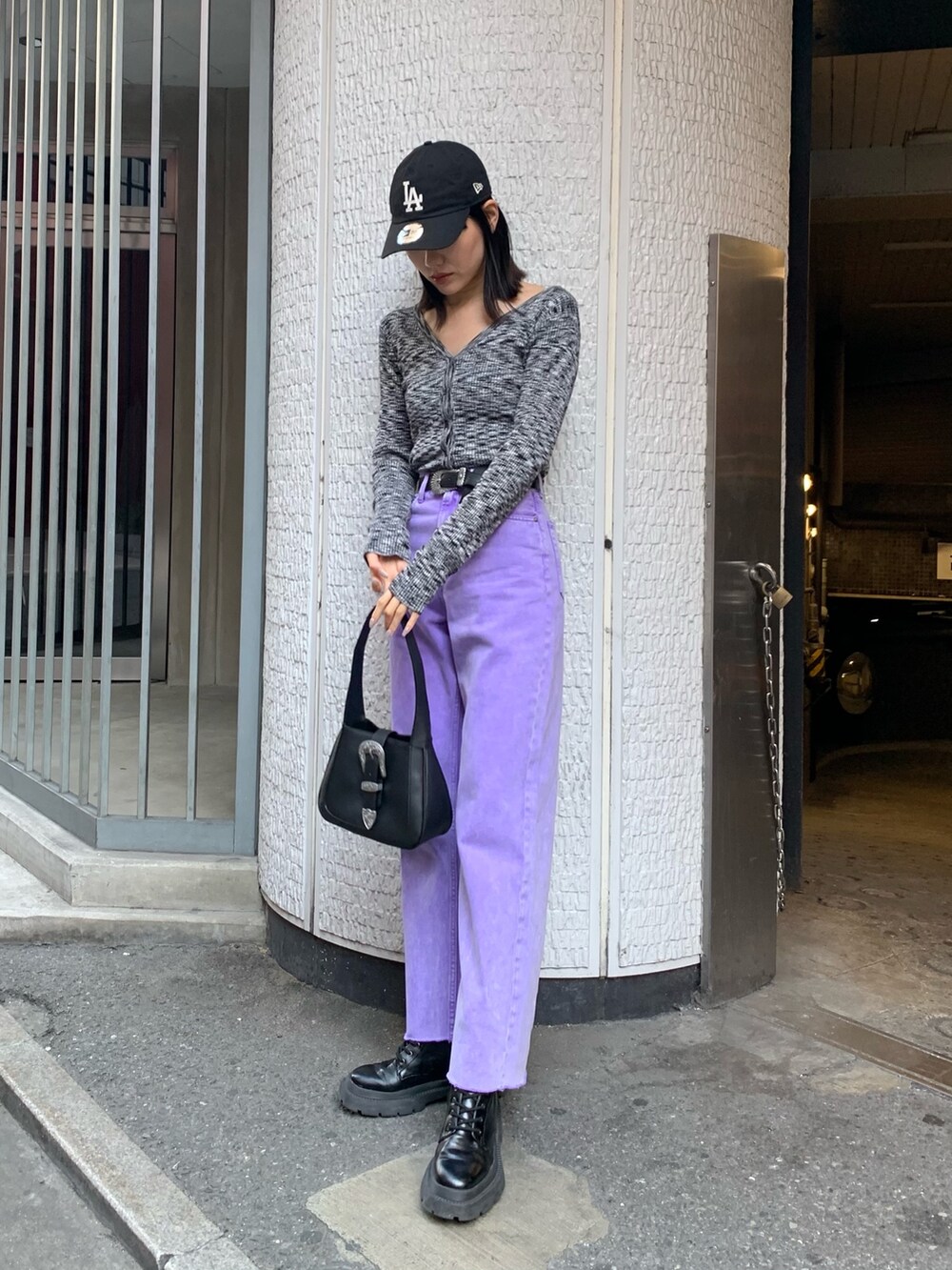 パープル系のデニムパンツ、ブラック系のニット/セーター、ブラック系のハンドバッグを着用したレディースの冬コーディネートの2枚目の写真