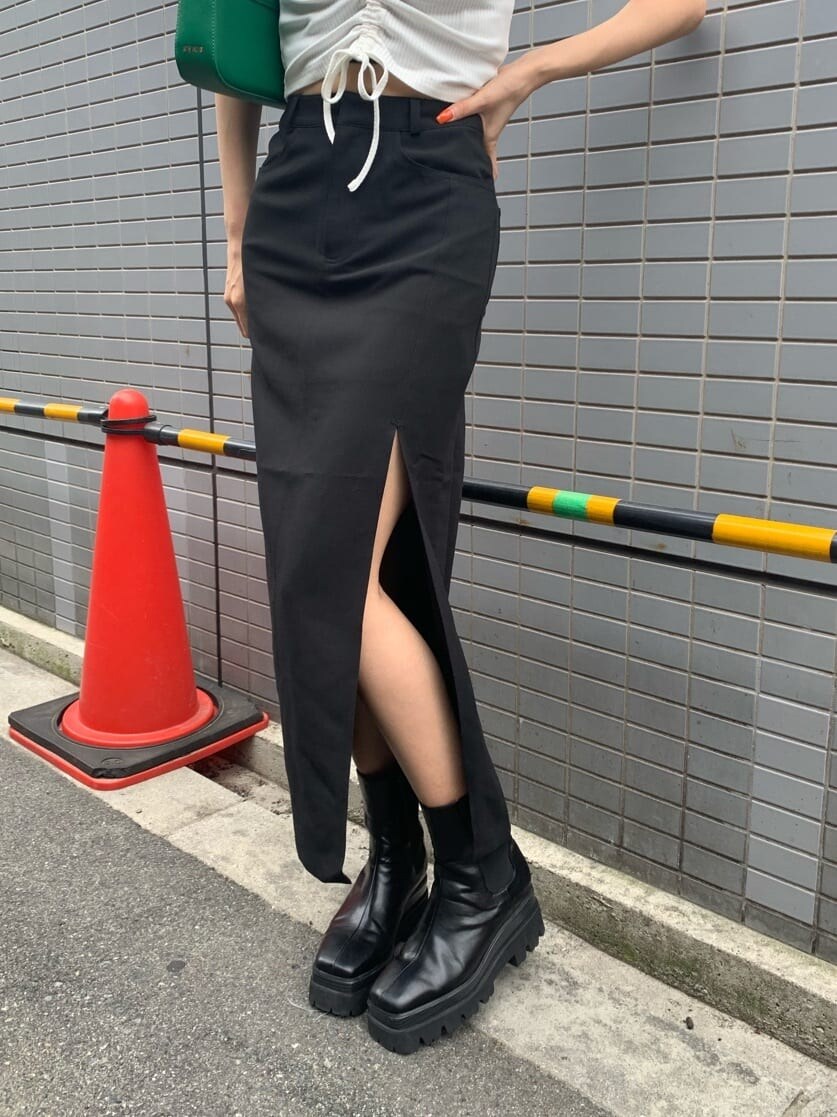 ブラック系のスカート、ブラック系のブーツ、グリーン系のショルダーバッグを着用したレディースの夏コーディネートの6枚目の写真