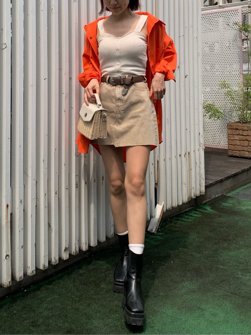 ブラック系のブーツ、ベージュ系のデニムスカート、オレンジ系のシャツ/ブラウスを着用したレディースの夏コーディネートの2枚目の写真