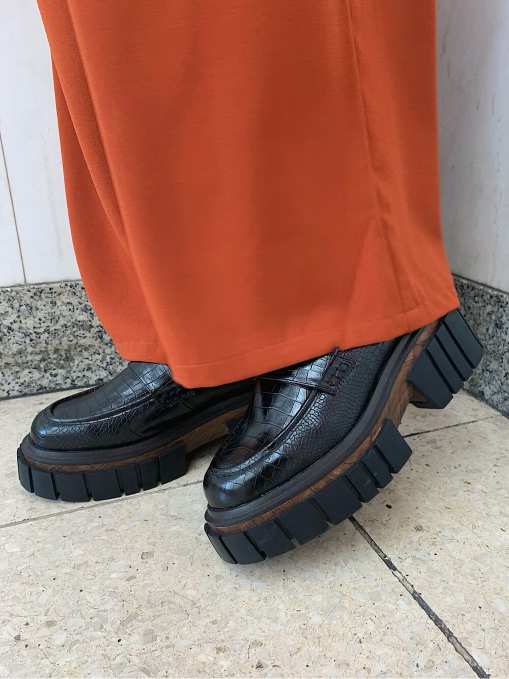 オレンジ系のその他パンツ、ブラック系のローファー、ブラック系のスマホケース/カバーを着用したレディースの秋コーディネートの7枚目の写真