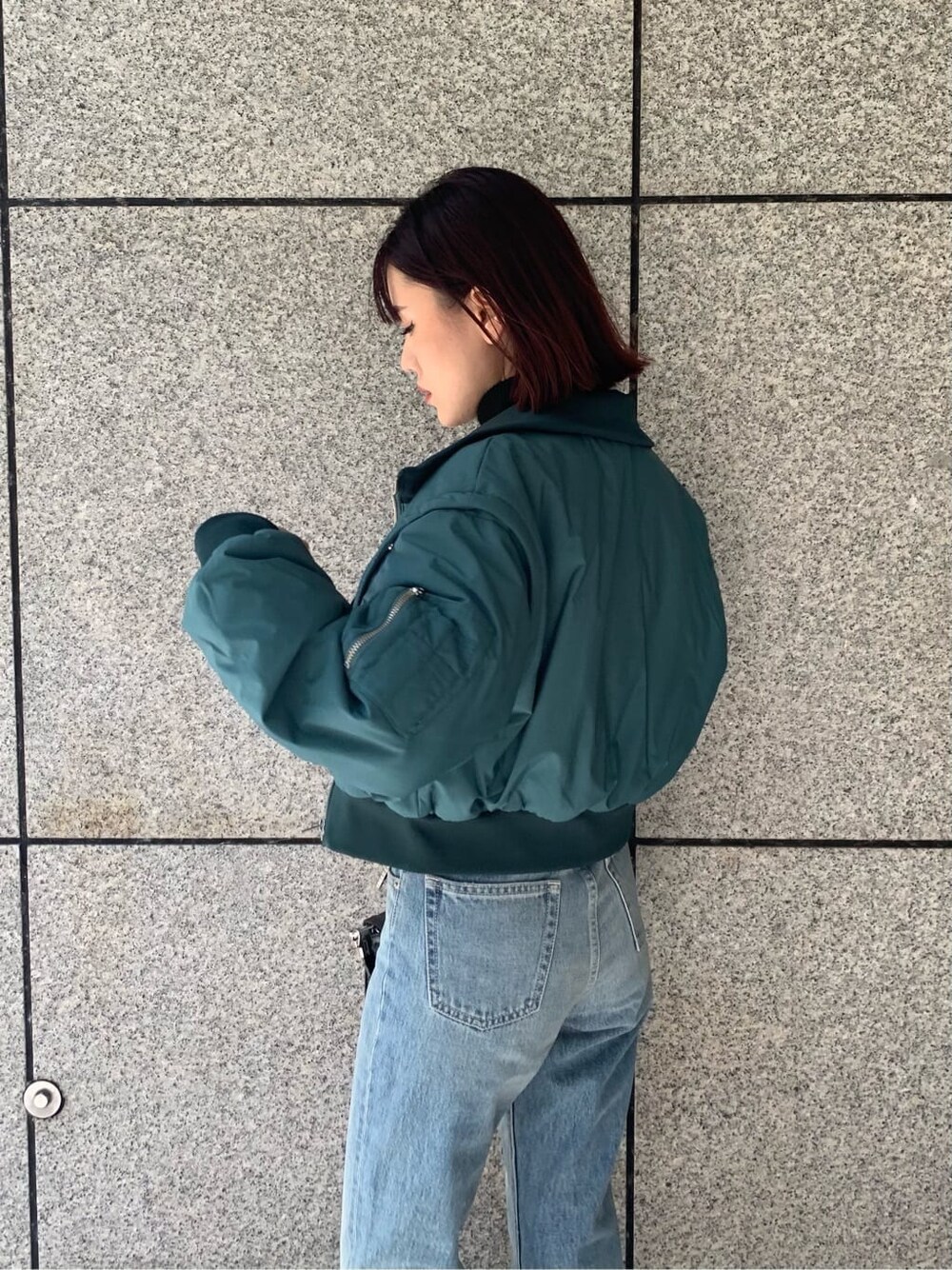 ブラック系のハンドバッグ、ブルー系のデニムパンツ、ブルー系のMA-1を着用したレディースの秋コーディネートの5枚目の写真