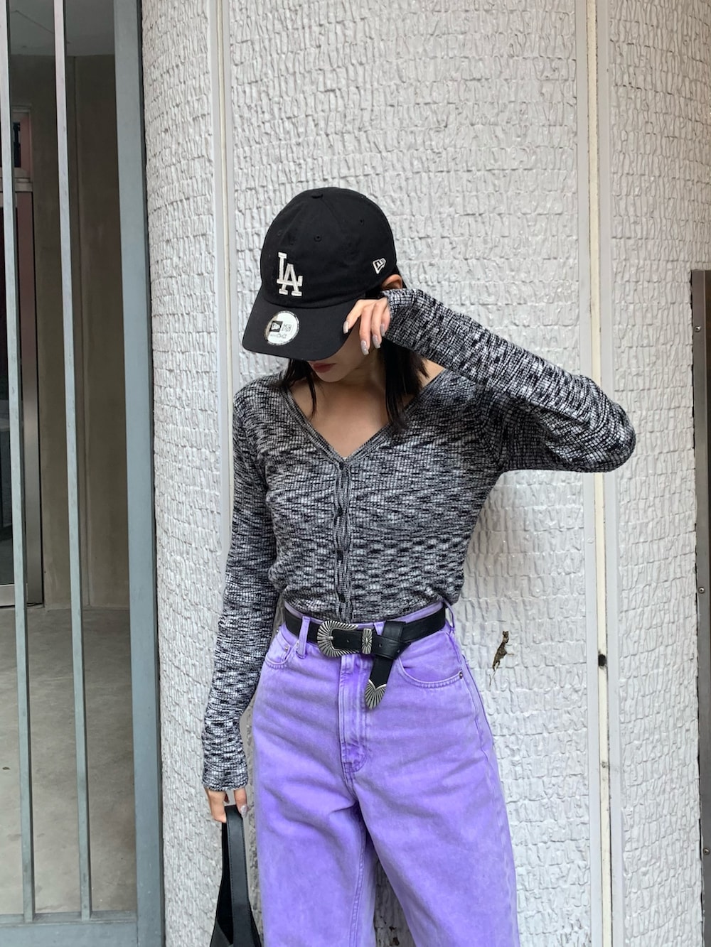パープル系のデニムパンツ、ブラック系のニット/セーター、ブラック系のハンドバッグを着用したレディースの冬コーディネートの4枚目の写真