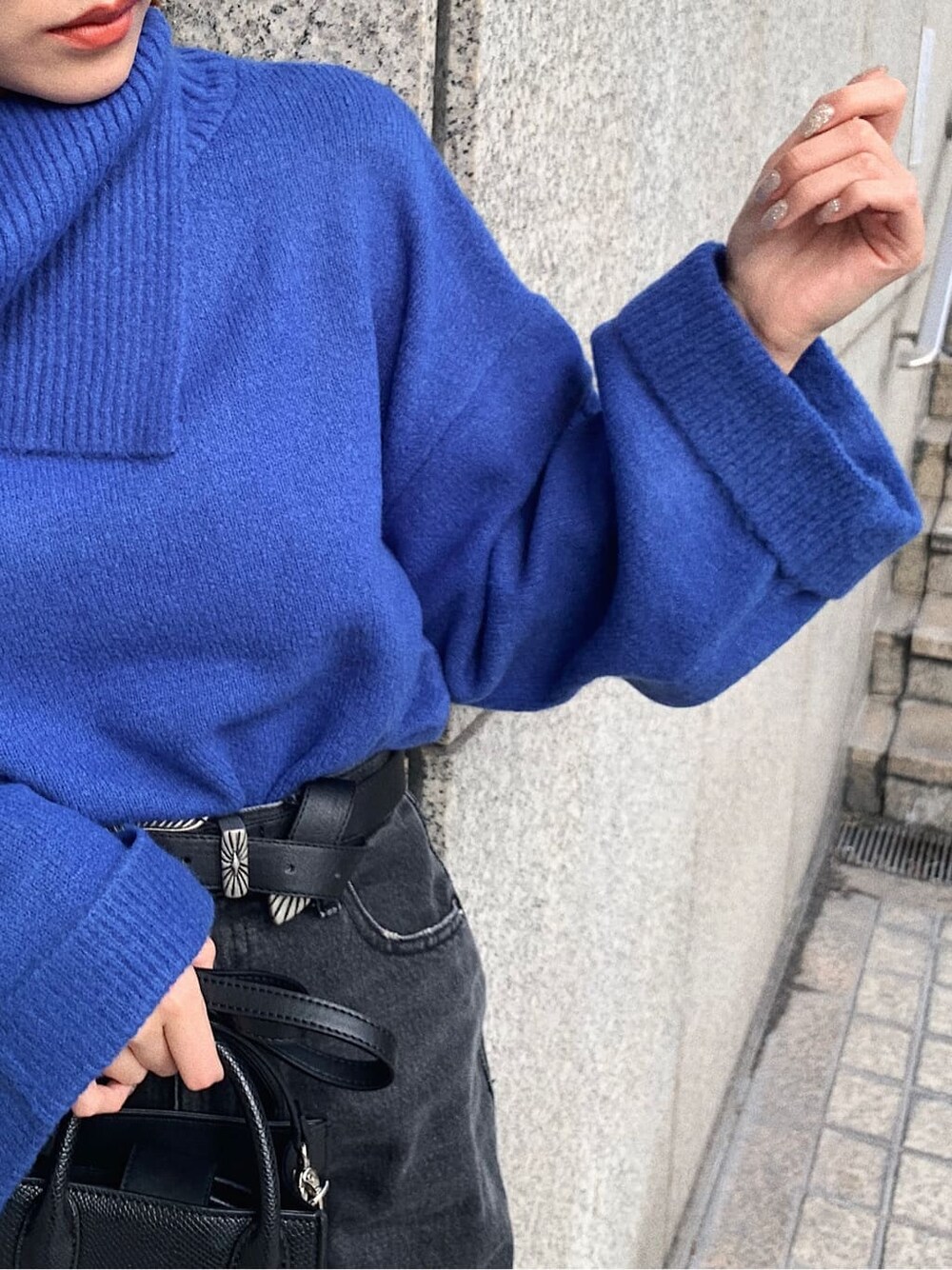 ブラック系のデニムパンツ、ブラック系のブーツ、ブラック系のショルダーバッグを着用したレディースの冬コーディネートの3枚目の写真