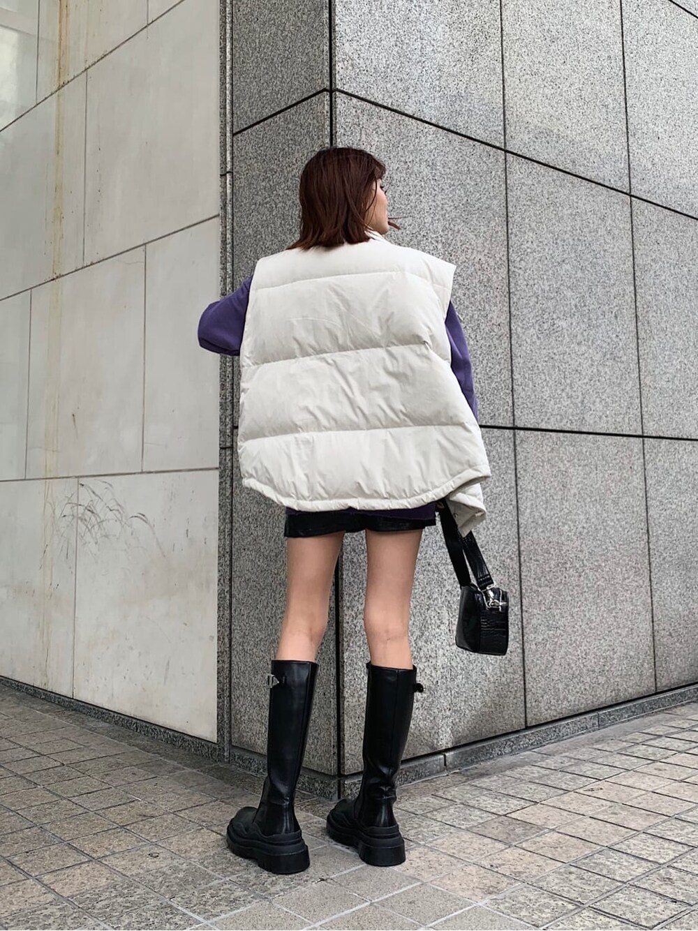 ホワイト系のダウンベスト、パープル系のスウェット、ブラック系のスカートを着用したレディースの秋コーディネートの2枚目の写真