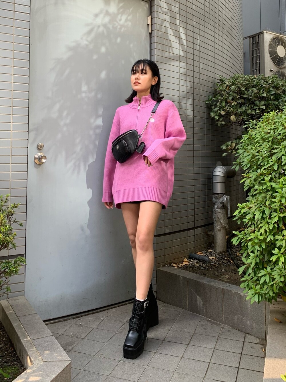 ピンク系のニット/セーター、ブラック系のブーツ、ブラック系のボディバッグ/ウエストポーチを着用したレディースの冬コーディネートの2枚目の写真