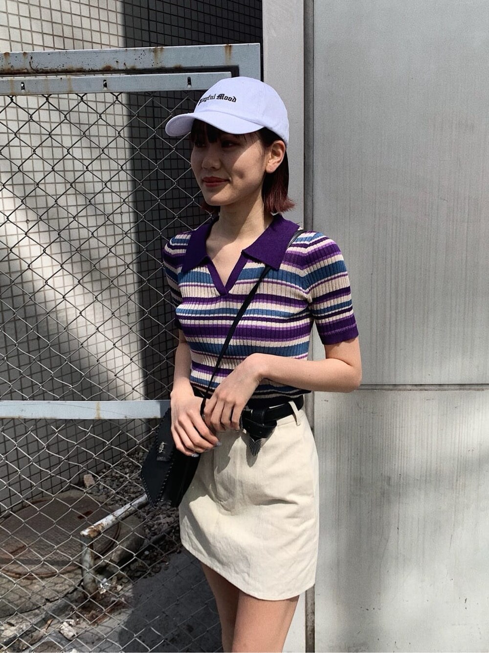 ブラック系のショルダーバッグ、ホワイト系のスカート、パープル系のニット/セーターを着用したレディースの春コーディネートの4枚目の写真