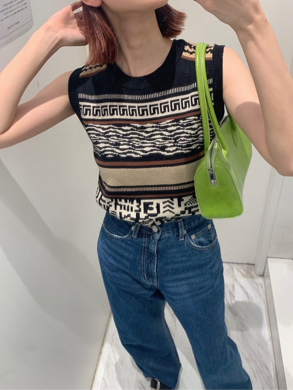 グリーン系のボストンバッグ、ブルー系のデニムパンツ、ブラック系のタンクトップを着用したレディースの夏コーディネートの3枚目の写真