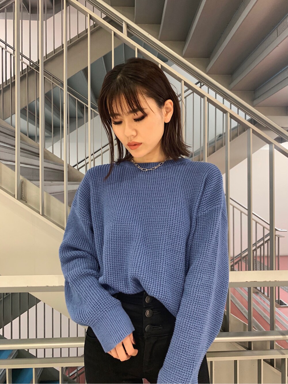 ブラック系のデニムパンツ、ホワイト系のショルダーバッグ、ブルー系のニット/セーターを着用したレディースの冬コーディネートの3枚目の写真