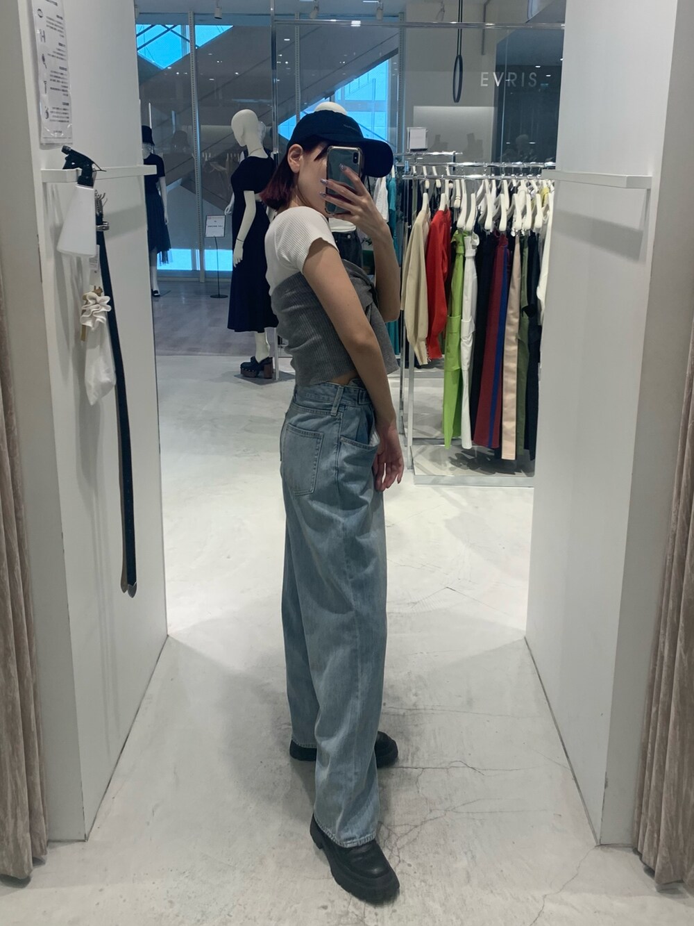 ブルー系のデニムパンツ、ブラック系のブーツ、グレー系のチューブトップを着用したレディースの春コーディネートの3枚目の写真