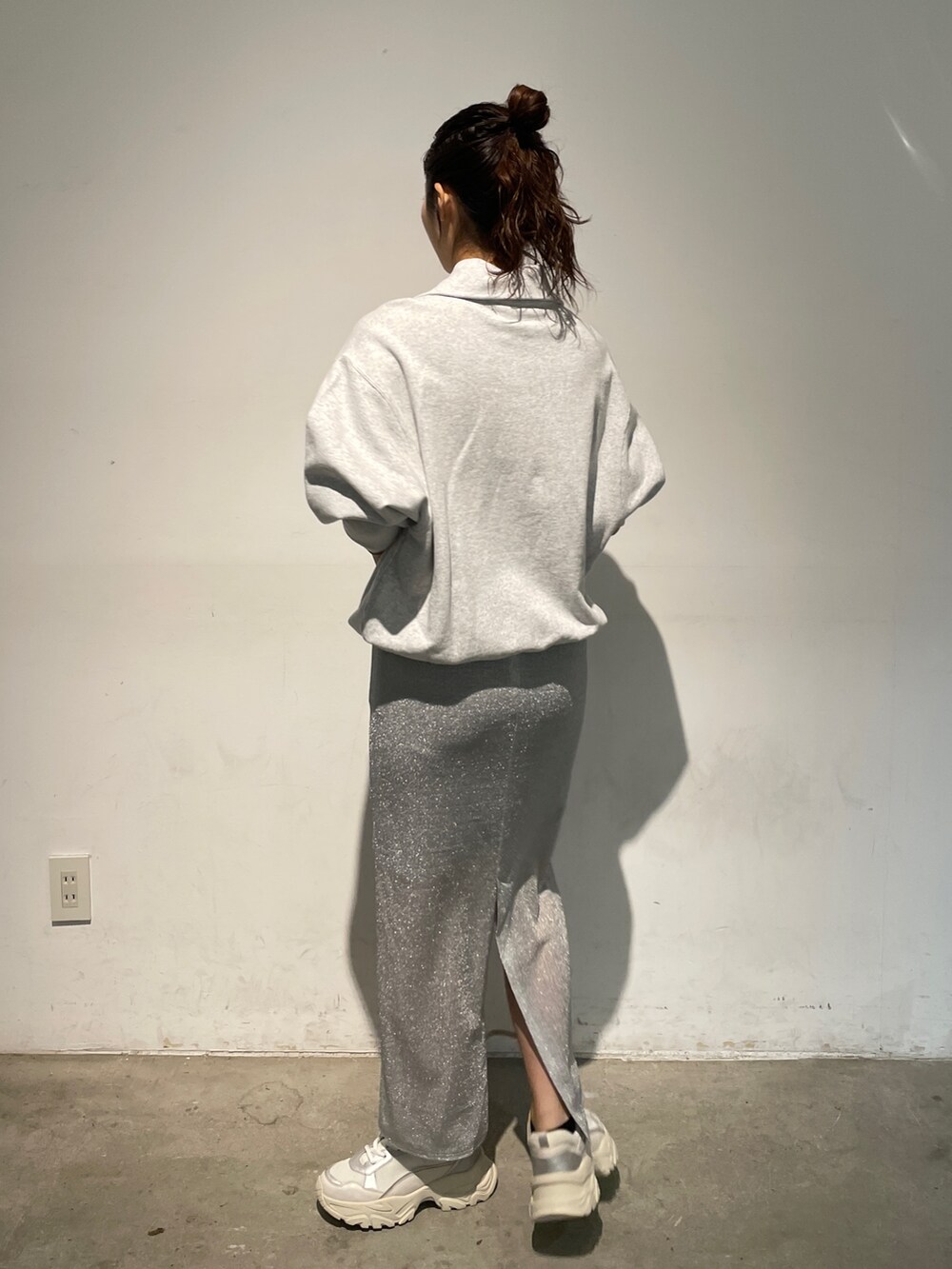 シルバー系のスカート、グレー系のスウェット、ホワイト系のスニーカーを着用したレディースの秋コーディネートの5枚目の写真