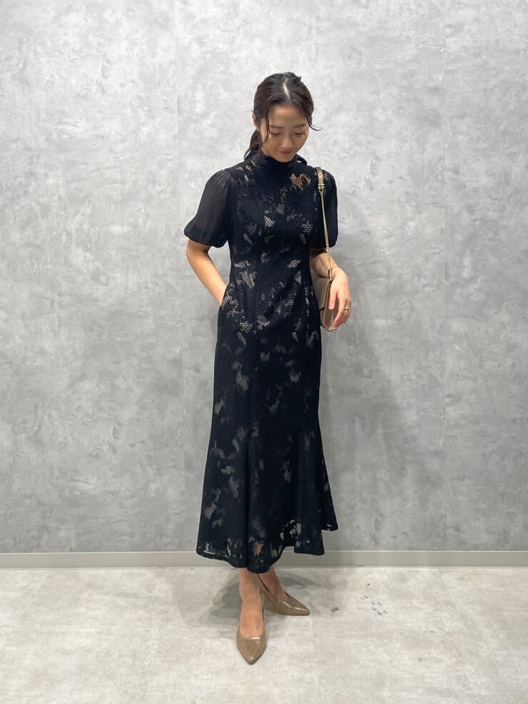 ゴールド系のパンプス、ゴールド系のクラッチバッグ、ブラック系のドレスを着用したレディースの秋コーディネートの3枚目の写真