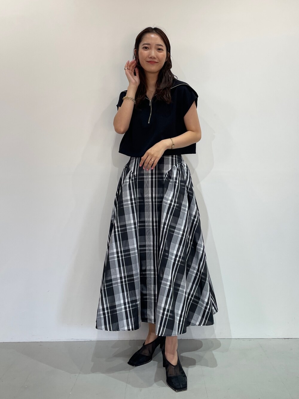 ブラック系のTシャツ/カットソー、ブラック系のパンプス、ホワイト系のスカートを着用したレディースの夏コーディネートの4枚目の写真