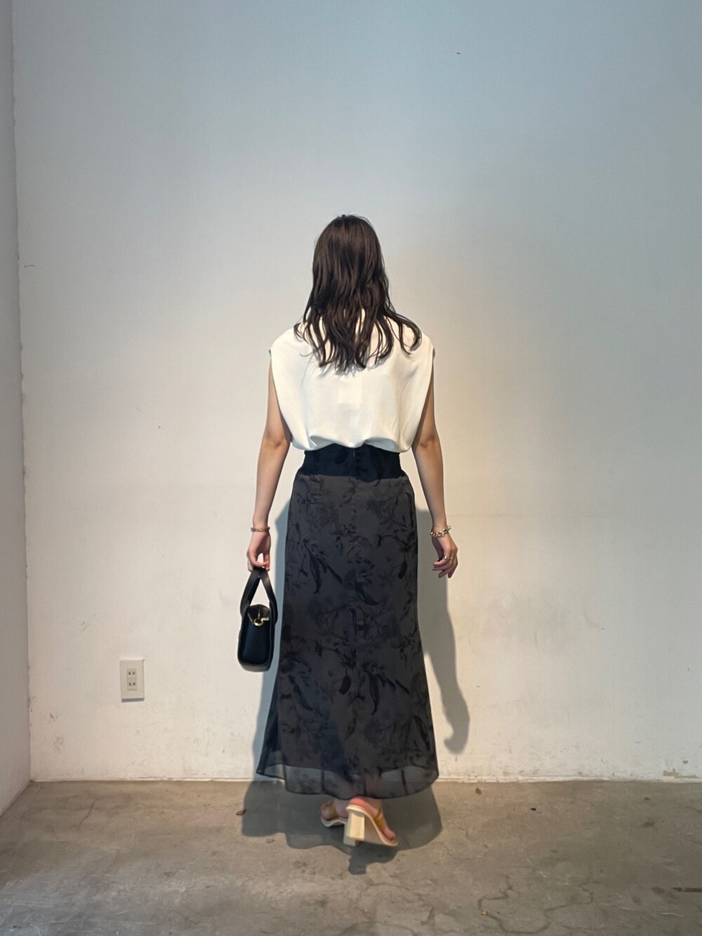 ホワイト系のニット/セーター、ブラック系のショルダーバッグ、イエロー系のサンダルを着用したレディースの夏コーディネートの4枚目の写真