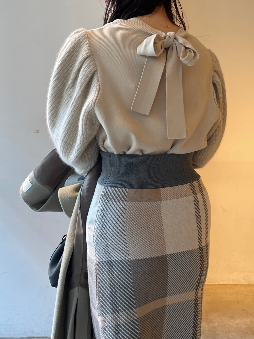 ブラック系のブーツ、ベージュ系のスカート、ホワイト系のニット/セーターを着用したレディースの冬コーディネートの5枚目の写真