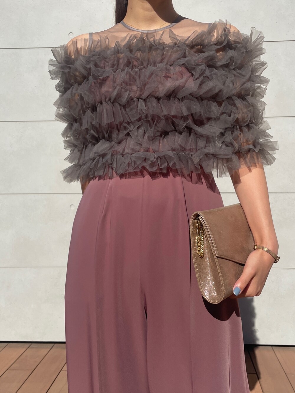 ピンク系のパンツドレス、ゴールド系のハンドバッグ、ベージュ系のパンプスを着用したレディースの秋コーディネートの4枚目の写真