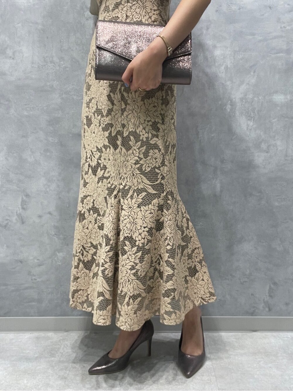 ベージュ系のドレス、シルバー系のパンプス、シルバー系のクラッチバッグを着用したレディースの夏コーディネートの8枚目の写真