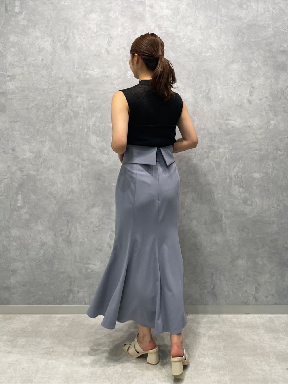 ホワイト系のサンダル、ブラック系のニット/セーター、ブルー系のスカートを着用したレディースの夏コーディネートの5枚目の写真