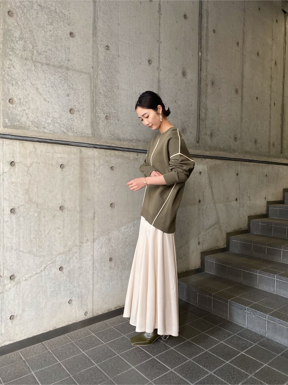 ホワイト系のスカート、ベージュ系のブーツ、ベージュ系のニット/セーターを着用したレディースの冬コーディネートの2枚目の写真