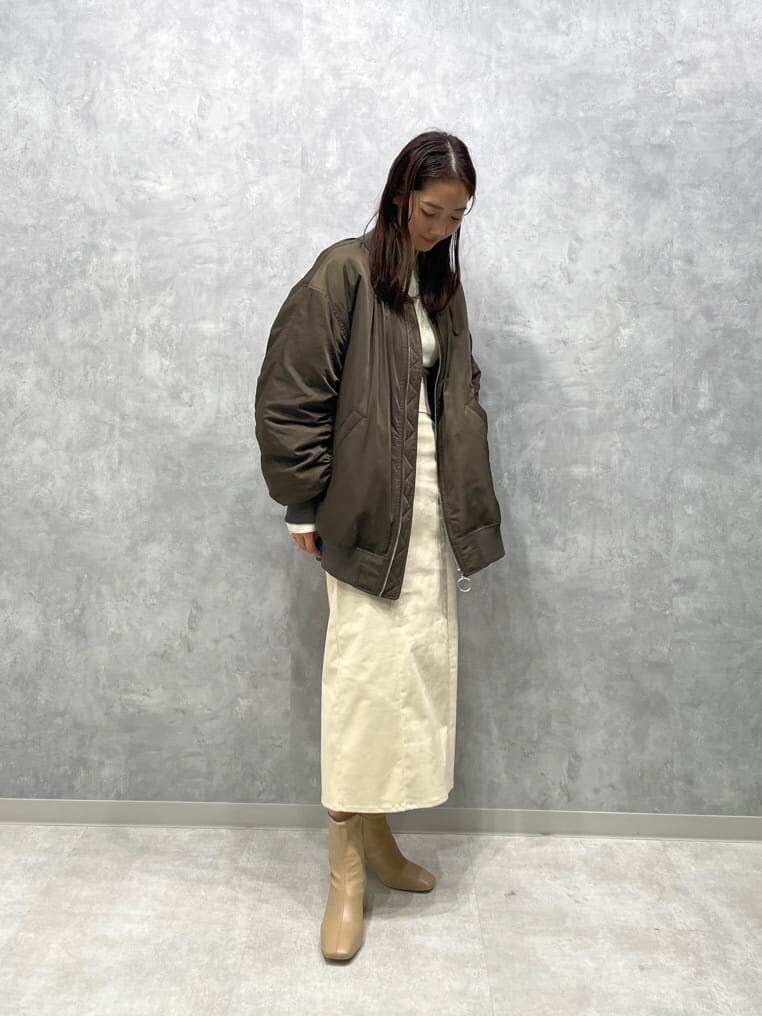 ベージュ系のブーツ、ホワイト系のニット/セーター、ブラウン系のMA-1を着用したレディースの秋コーディネートの3枚目の写真