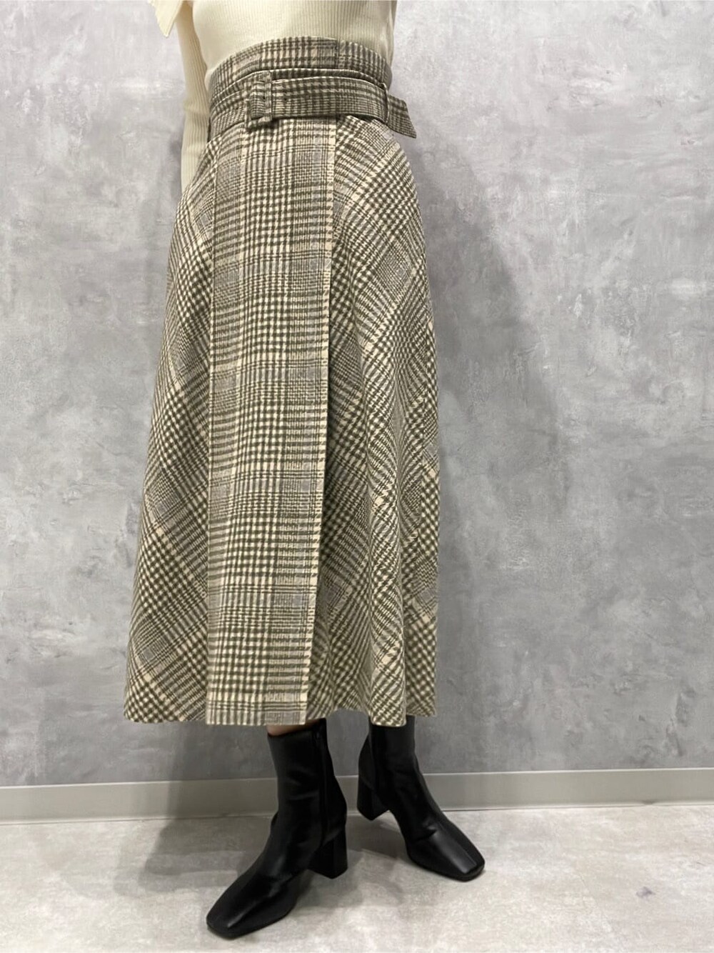 ブラック系のブーツ、ベージュ系のスカート、ホワイト系のニット/セーターを着用したレディースの秋コーディネートの9枚目の写真