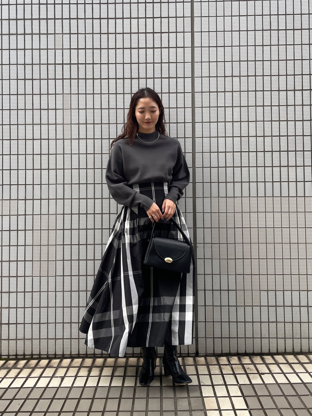 ブラック系のワンピース、ブラック系のブーツ、ブラック系のハンドバッグを着用したレディースの冬コーディネートの4枚目の写真