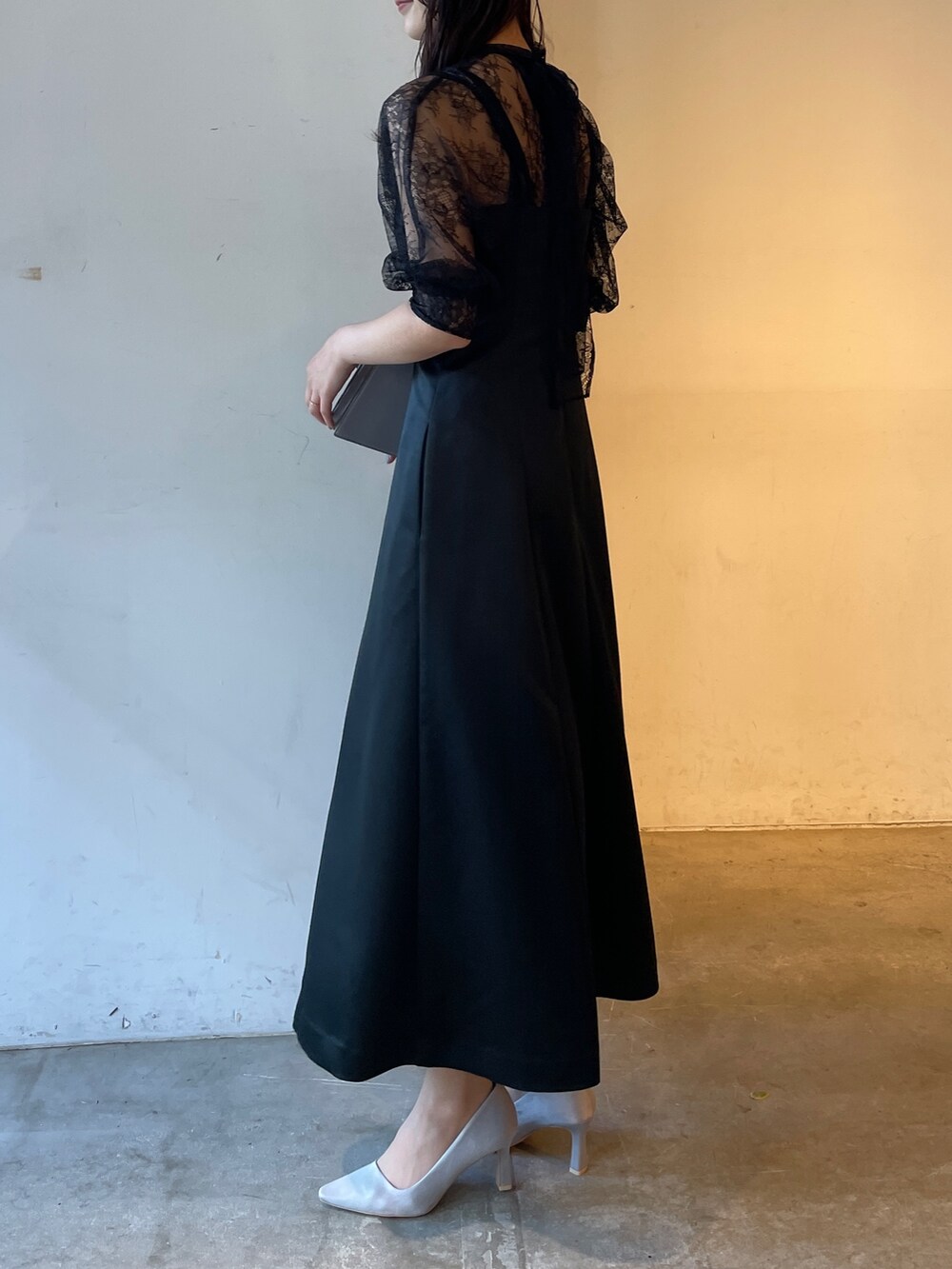 グレー系のパンプス、ブラック系のドレス、グレー系のクラッチバッグを着用したレディースの冬コーディネートの8枚目の写真