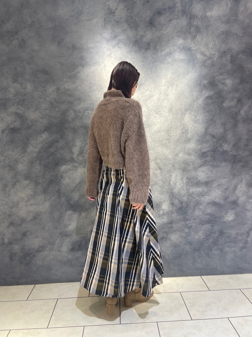 ブラウン系のニット/セーター、オレンジ系のスカート、ベージュ系のブーツを着用したレディースの秋コーディネートの5枚目の写真