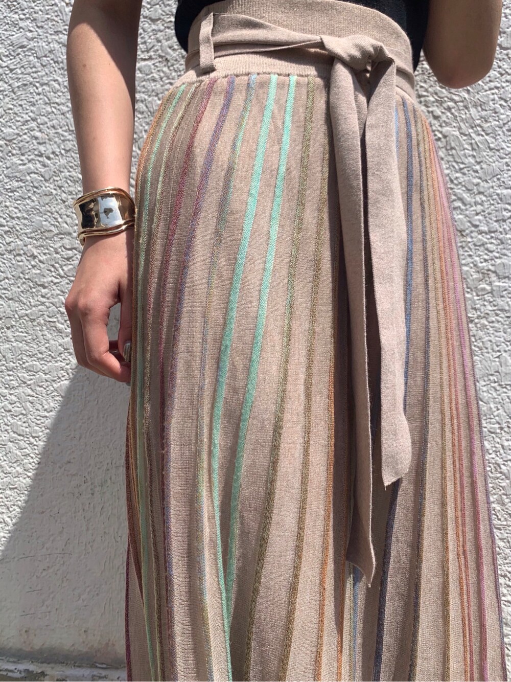 ベージュ系のスカート、ブラック系のニット/セーター、ゴールド系のバングル/リストバンドを着用したレディースの春コーディネートの7枚目の写真