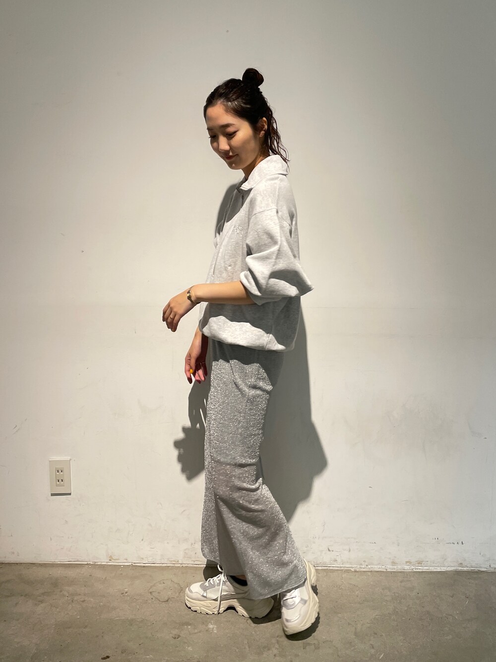 シルバー系のスカート、グレー系のスウェット、ホワイト系のスニーカーを着用したレディースの秋コーディネートの4枚目の写真