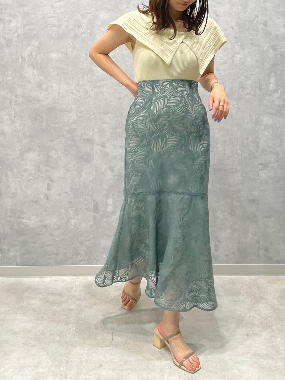 グリーン系のサンダル、ブルー系のスカート、ホワイト系のニット/セーターを着用したレディースの夏コーディネートの3枚目の写真