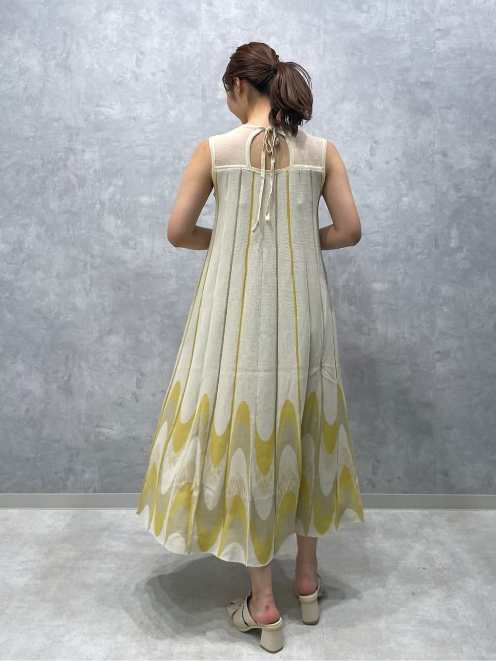 ホワイト系のサンダル、イエロー系のワンピースを着用したレディースの夏コーディネートの5枚目の写真