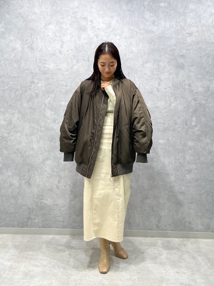 ベージュ系のブーツ、ホワイト系のニット/セーター、ブラウン系のMA-1を着用したレディースの秋コーディネートの4枚目の写真