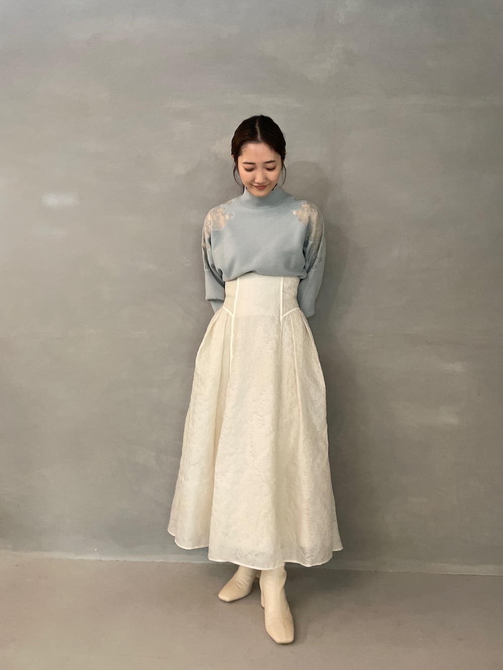 グレー系のニット/セーター、ホワイト系のスカート、ホワイト系のブーツを着用したレディースの夏コーディネートの4枚目の写真