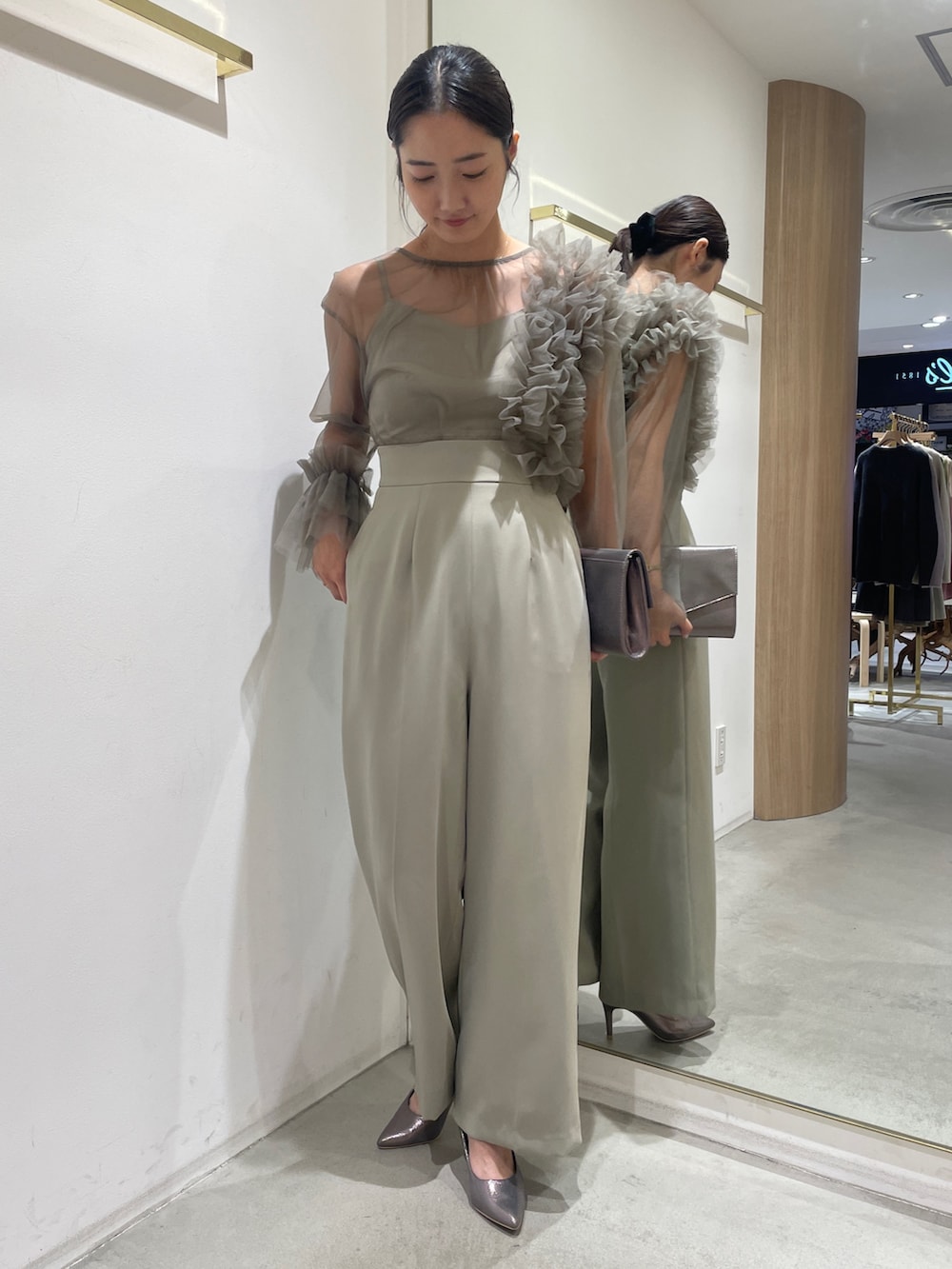 グリーン系のパンツドレス、シルバー系のハンドバッグ、シルバー系のパンプスを着用したレディースの冬コーディネートの4枚目の写真